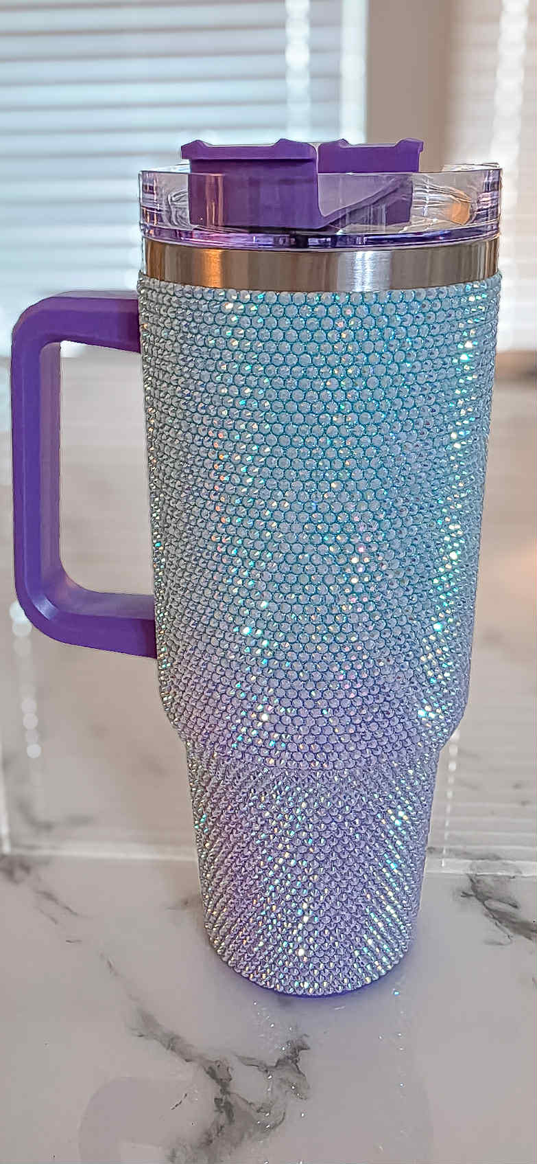 Blinged-out tumbler with purple handle on a marble surface