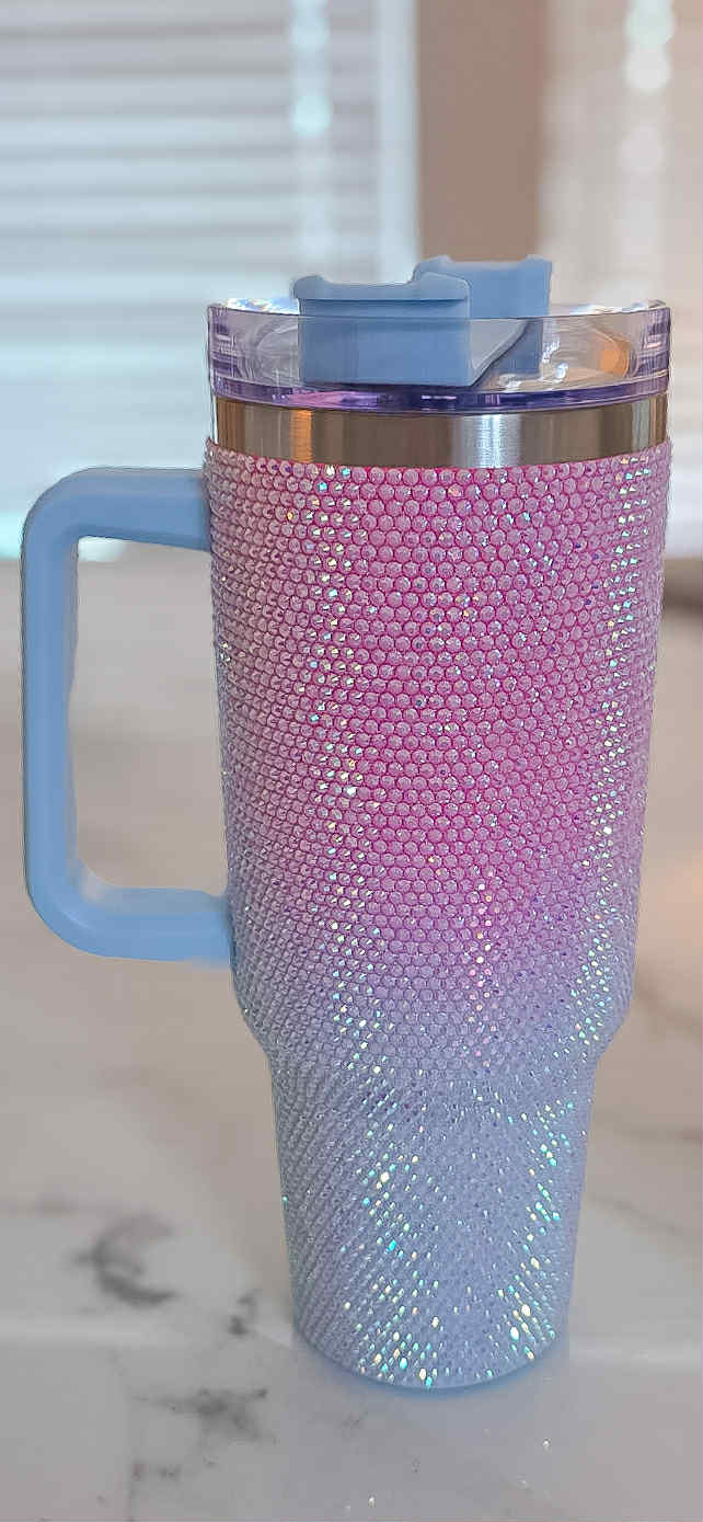 Pink and blue glittery tumbler with handle on a marble surface