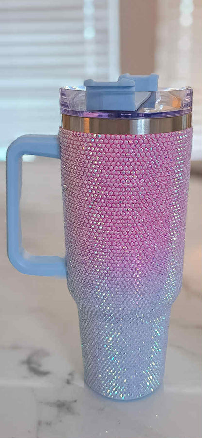 Pink and blue glittery tumbler with handle on a marble surface