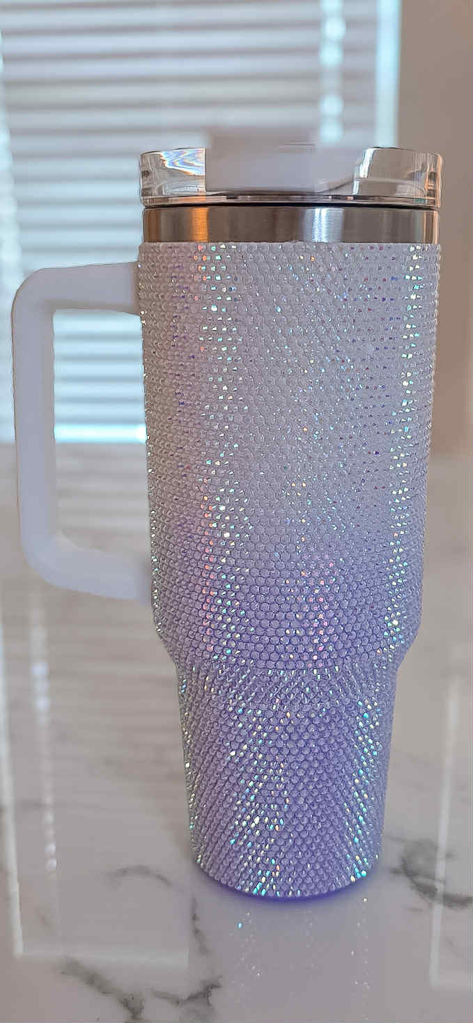 Blush pink tumbler with rhinestone embellishments on a marble surface.